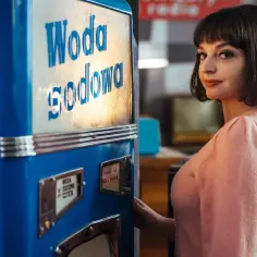 Kadr z filmu o Kalinie Jędrusik. Młoda kobieta w różowym swetrze przy sodostacji.