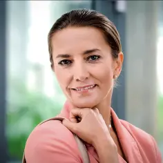Uśmiechnięta Kamilla Baar, gwiazda filmów, seriali i programów, w różowej marynarce.