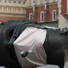 Fragment rzeźby Igora Mitoraja w Krakowie z gołębiem i jasnoróżową tkaniną.