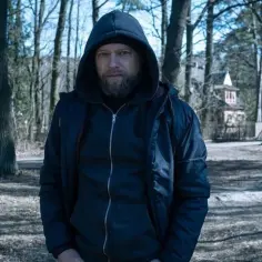 Maciej Stuhr w kapturze, z brodą, w lesie. Może to scena z jednego z jego filmów?