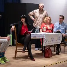 Scena z życia, gdzie teatr dla dorosłych ukazuje rodzinne napięcia przy stole.