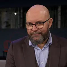 Szymon Bobrowski w garniturze i okularach, opowiada o swoich filmach, serialach i programach.