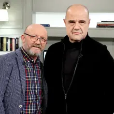Dwóch mężczyzn, jeden w marynarce, drugi w czarnej kurtce, rozmawia o filmach Artura Barcisia.