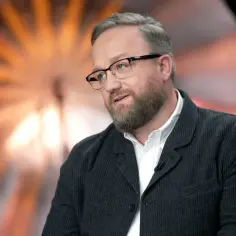 Bartłomiej Kasprzykowski w okularach i marynarce, opowiadający o swoich filmach.
