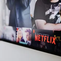 Ekran telewizora z widocznymi okładkami filmów i seriali. Widać logo Netflix i napis "Netflix nowości polskie".