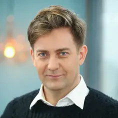 Rafał Królikowski, znany z wielu filmów, z niebieskimi oczami i uśmiechem.