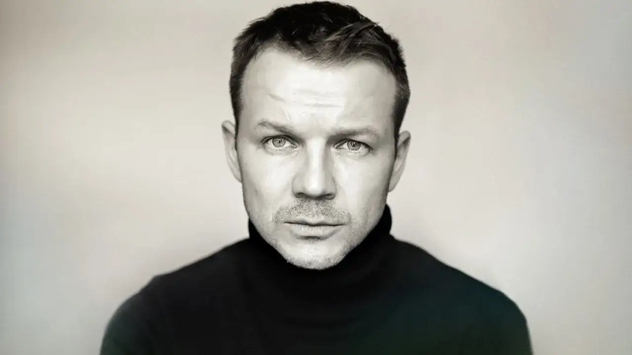 Portret mężczyzny w czarnym golfie, zamyślony wzrok. Może to Lesław Żurek, aktor znany z wielu filmów.