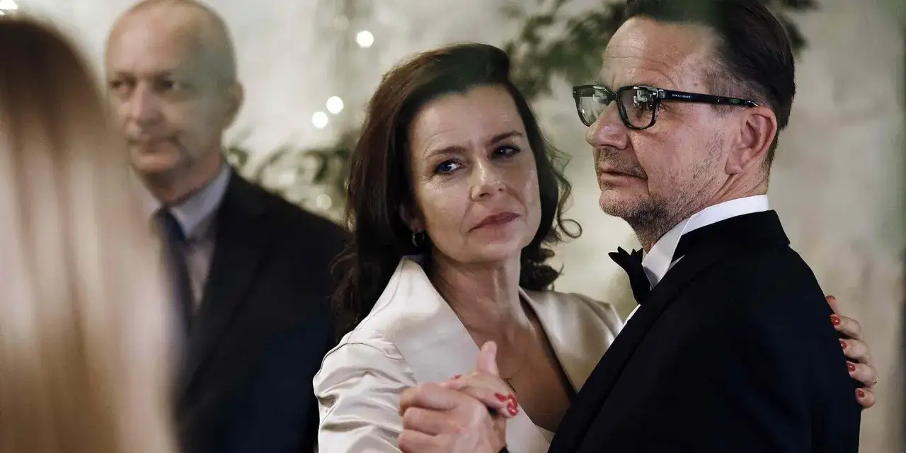 Agata Kulesza w eleganckiej kreacji, tańczy z partnerem. W tle widać innych uczestników uroczystości.