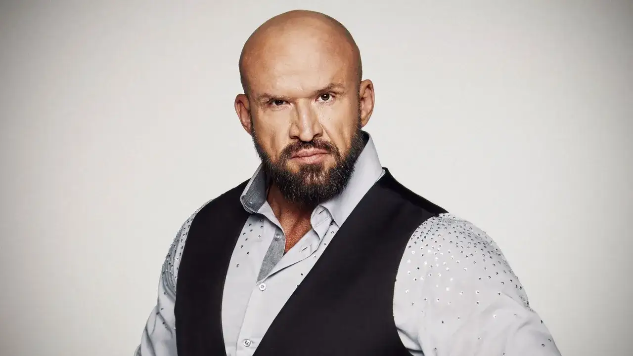 Tomasz Oświeciński, znany z wielu filmów, w eleganckiej stylizacji: łysy, z brodą, w koszuli i kamizelce.